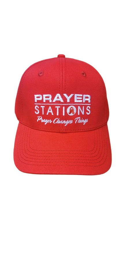 Red cap with 'Prayer Stations' text on a textured surface